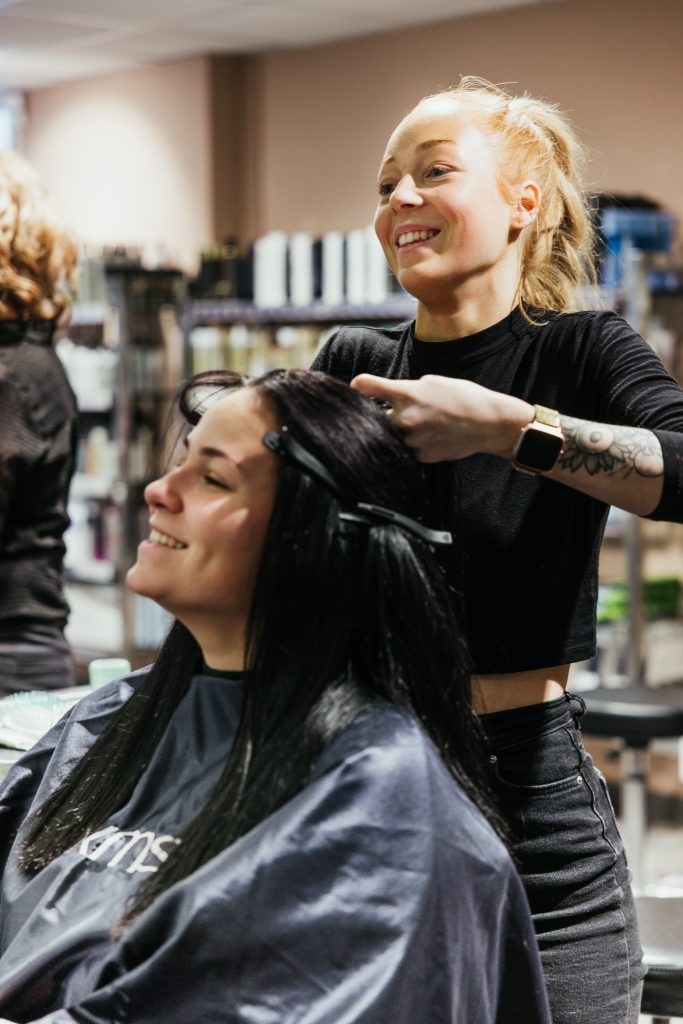 Frisørlærling som klipper håret til en kunde. Foto